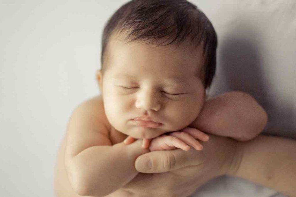 Imagen de un bebé recién nacido dormido plácidamente sobre una manta en estudio fotográfico en Valencia, capturado de forma natural y profesional.