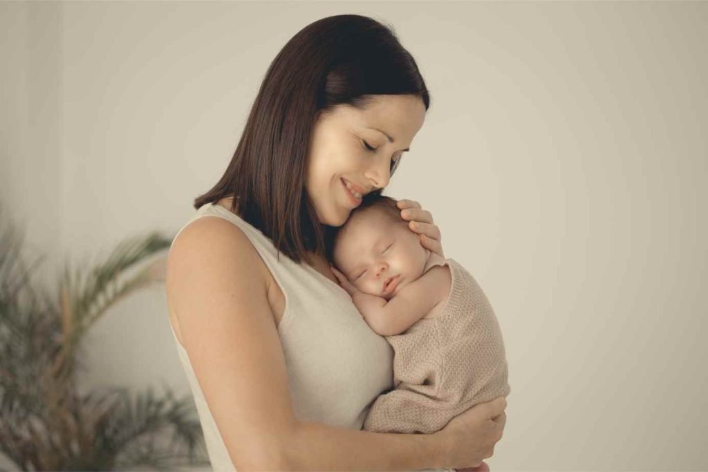 Fotografía emotiva de una madre sosteniendo a su recién nacido en brazos durante una sesión newborn en Valencia, en un entorno íntimo y acogedor.